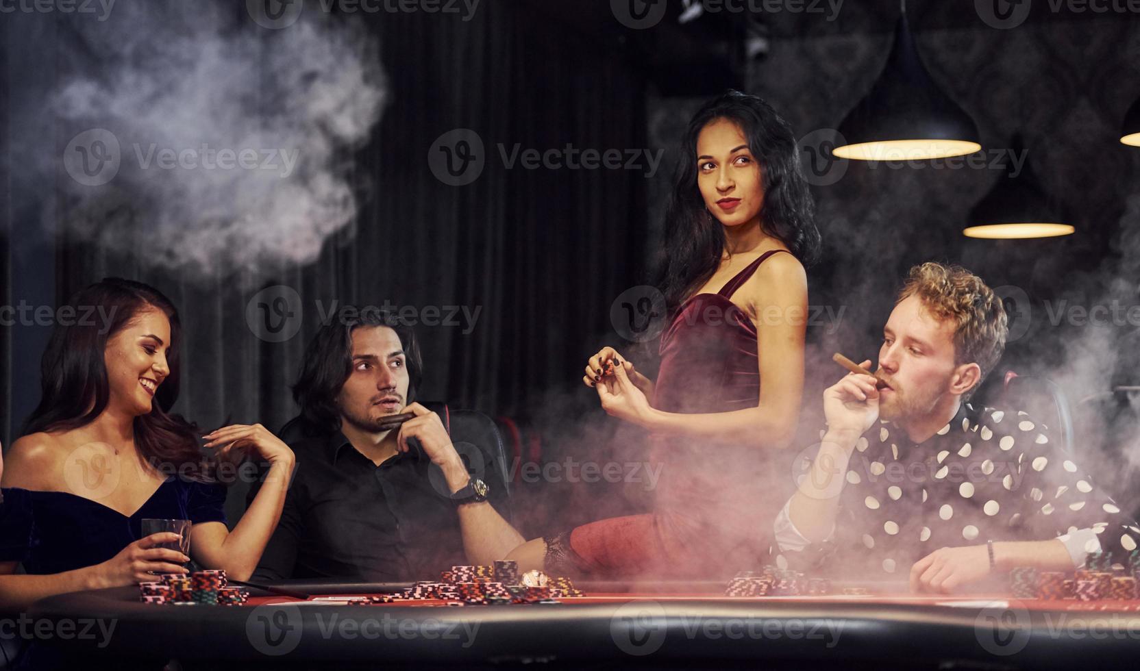 Gruppe eleganter junger Leute, die zusammen im Casino Poker spielen foto