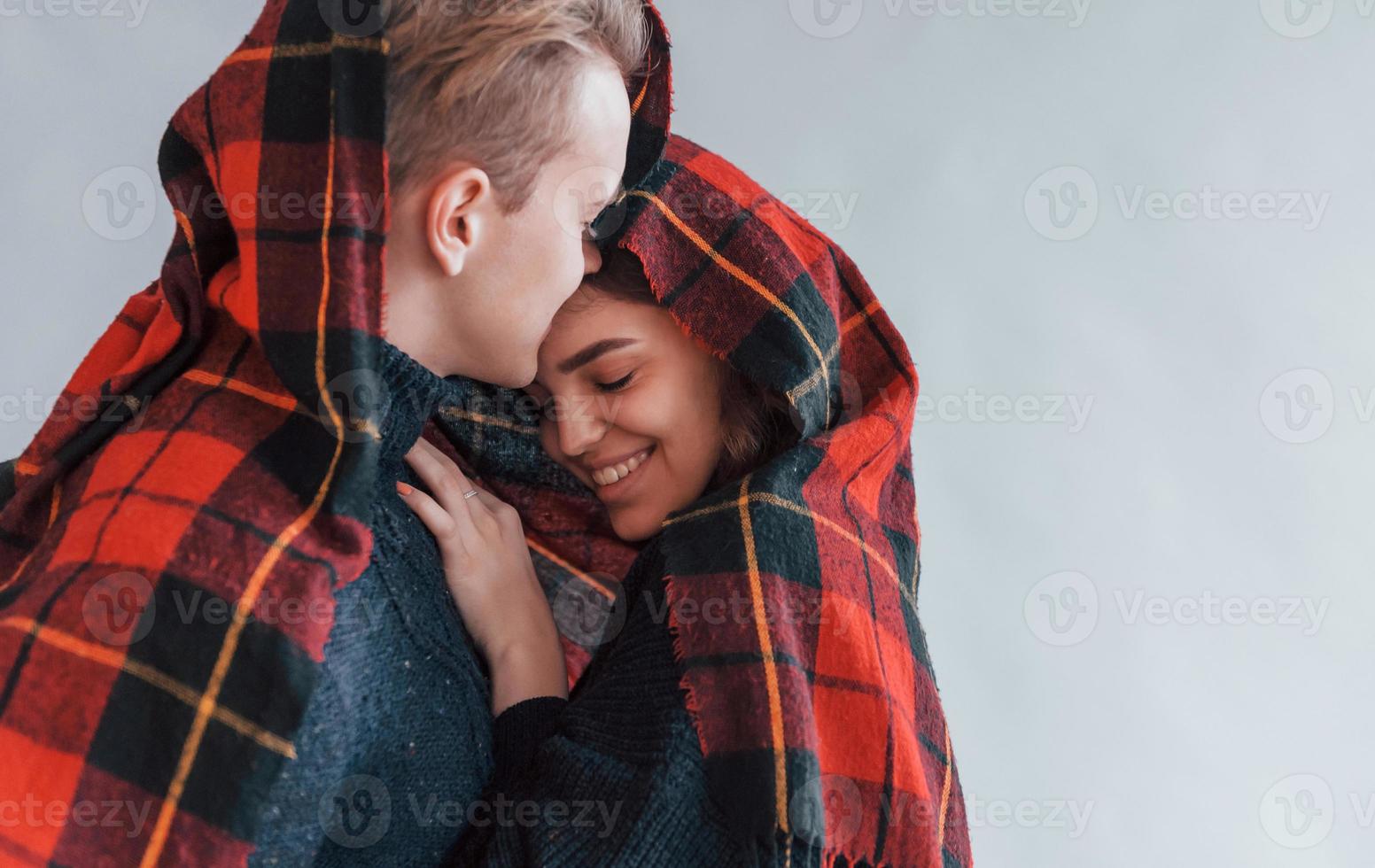 mit rotem Tuch. Süßes junges Paar, das sich drinnen im Studio umarmt foto