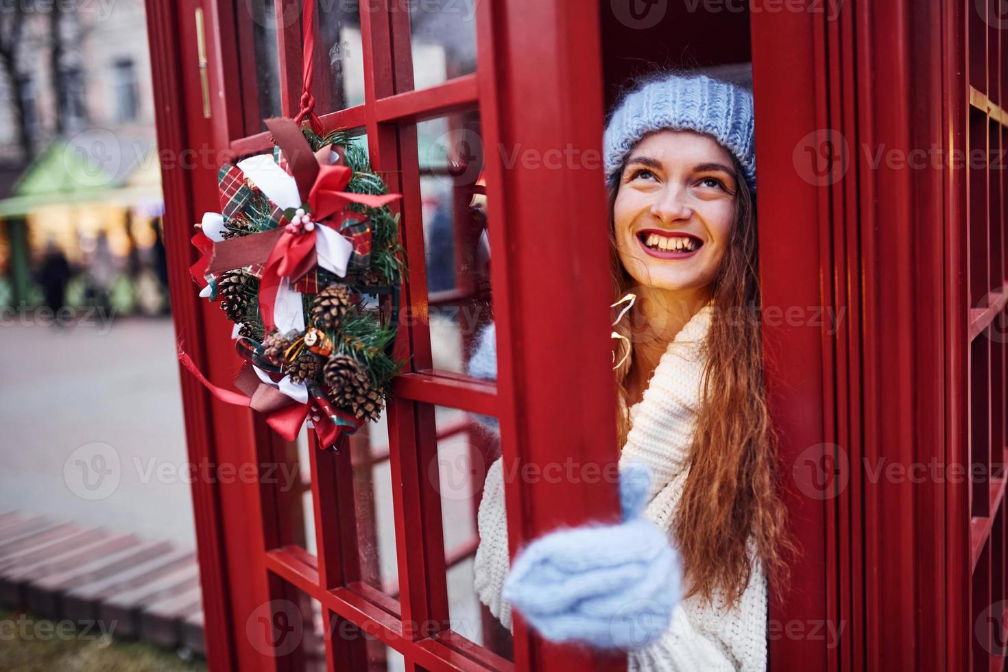 frau in warmer kleidung hat spaß in der telefonstation. schönes Mädchen foto