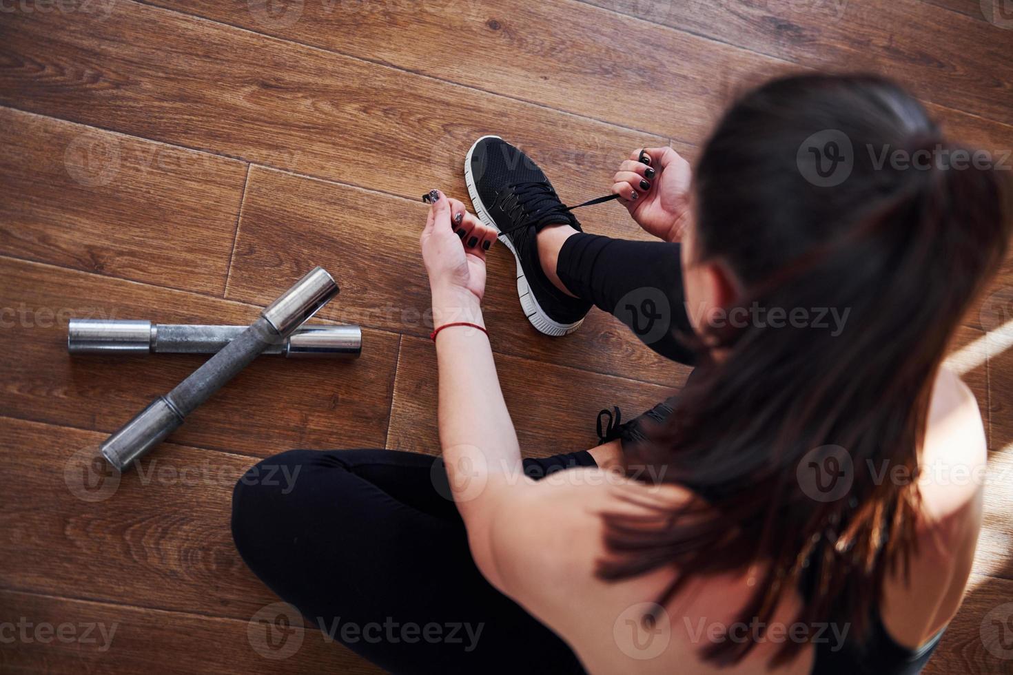 auf dem von Lichtstrahlen beleuchteten Boden. junge sportliche Frau in Sportbekleidung, die sich auf das Training vorbereitet foto