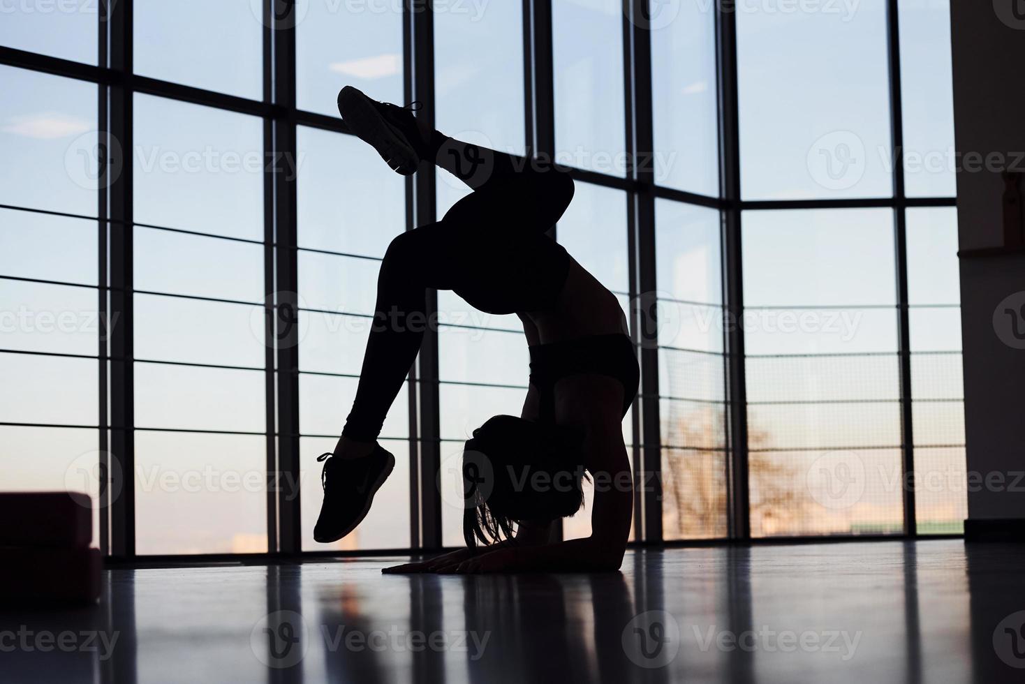 Silhouette einer jungen sportlichen Frau in Sportbekleidung, die Fitness im Fitnessstudio macht foto