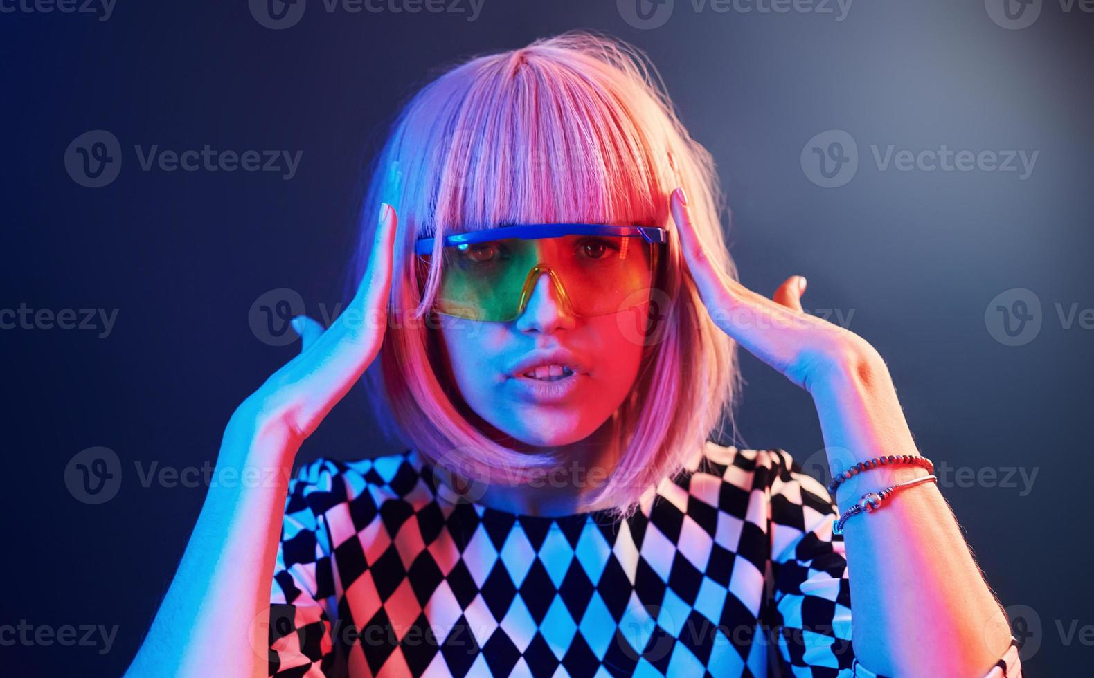 Porträt eines jungen Mädchens mit blonden Haaren in Brillen in rotem und blauem Neon im Studio foto