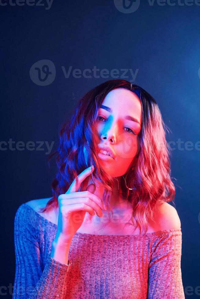 Porträt eines jungen Mädchens mit lockigem Haar in rotem und blauem Neon im Studio foto