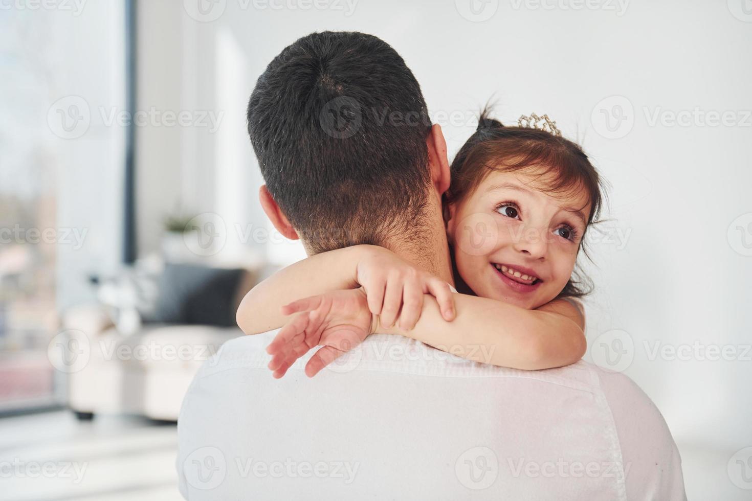 Glücklicher Vater mit seiner Tochter, die sich zu Hause umarmt foto