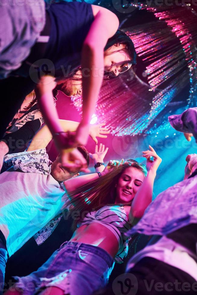 Blick von unten auf junge Leute, die sich im Nachtclub mit bunten Laserlichtern amüsieren foto