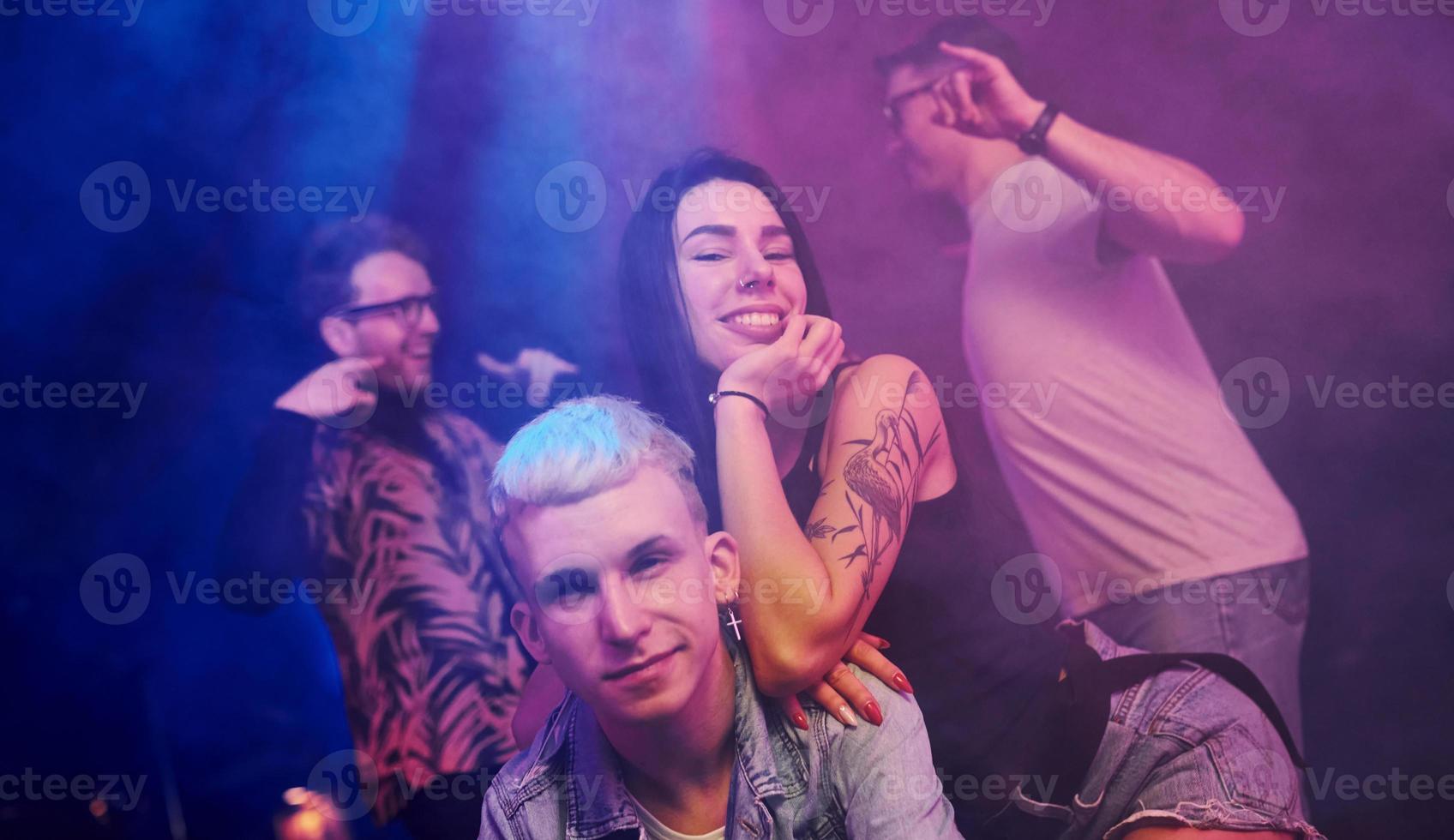 verrückt werden und gemeinsam für die Kamera posieren. junge leute haben spaß im nachtclub mit bunten laserlichtern foto