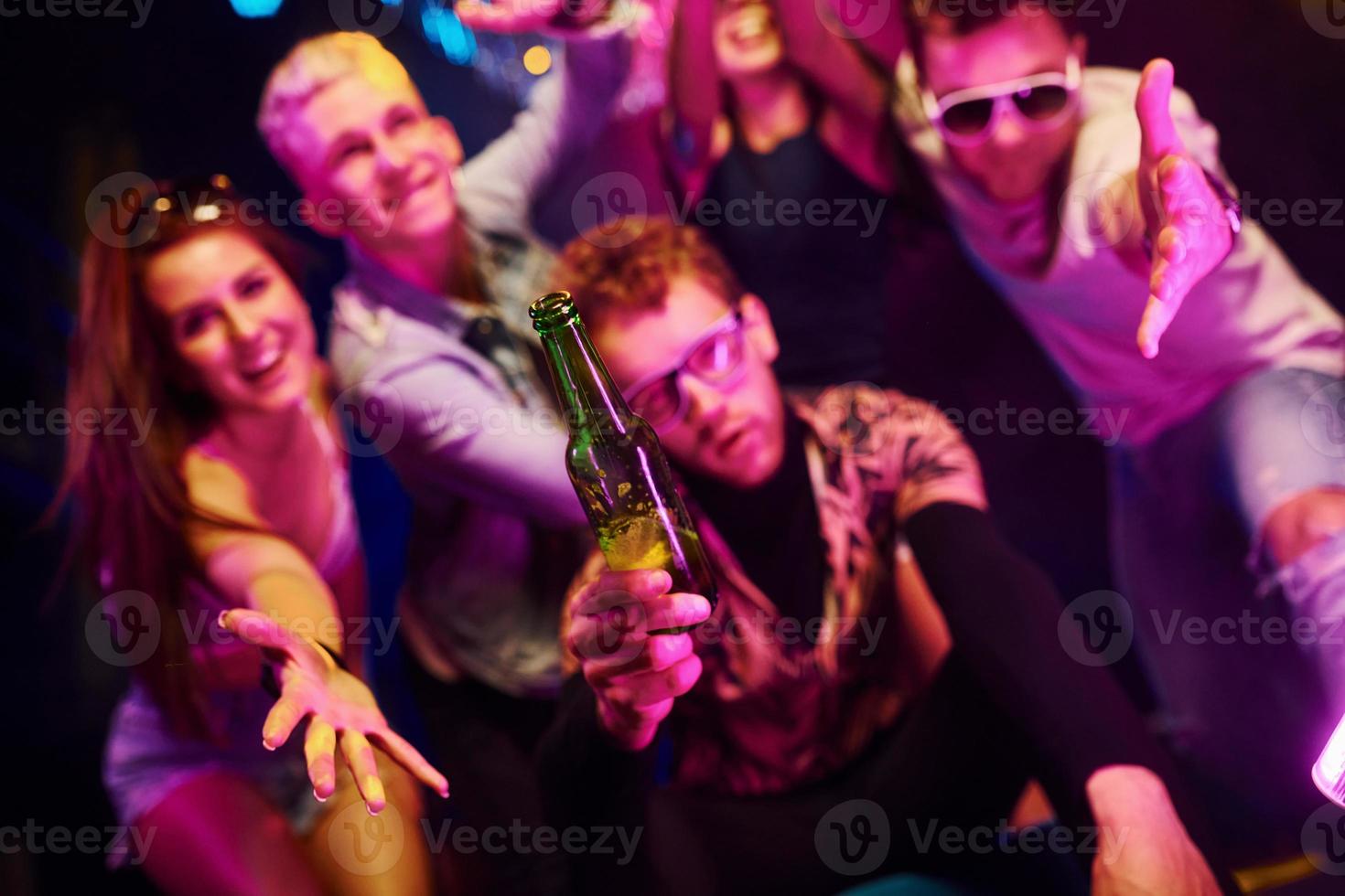 verrückt werden und gemeinsam für die Kamera posieren. junge leute haben spaß im nachtclub mit bunten laserlichtern foto