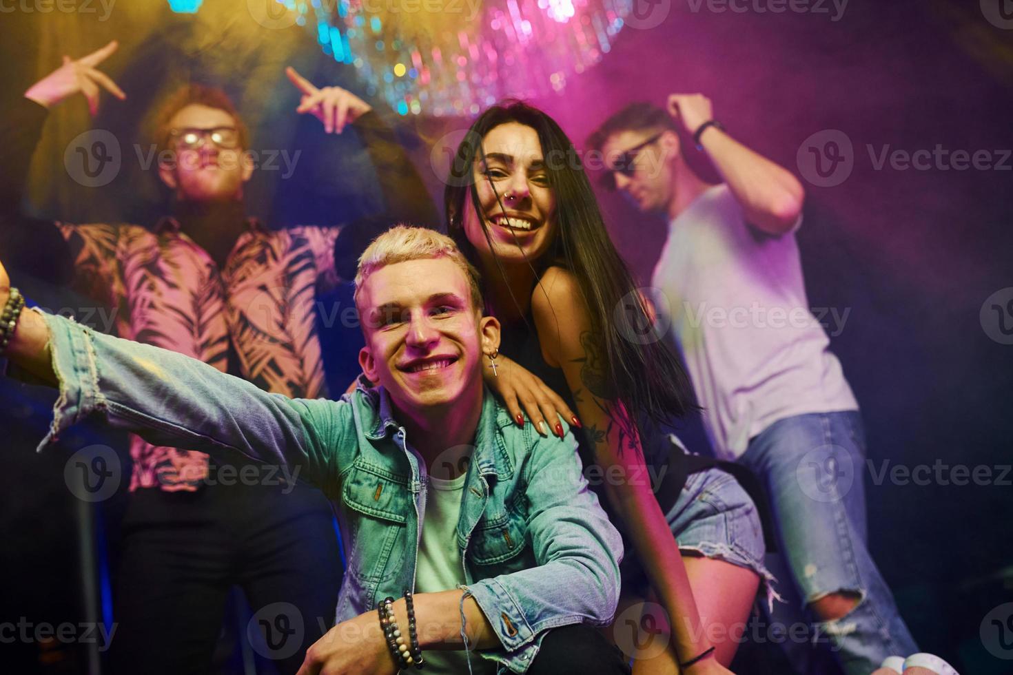 verrückt werden und gemeinsam für die Kamera posieren. junge leute haben spaß im nachtclub mit bunten laserlichtern foto