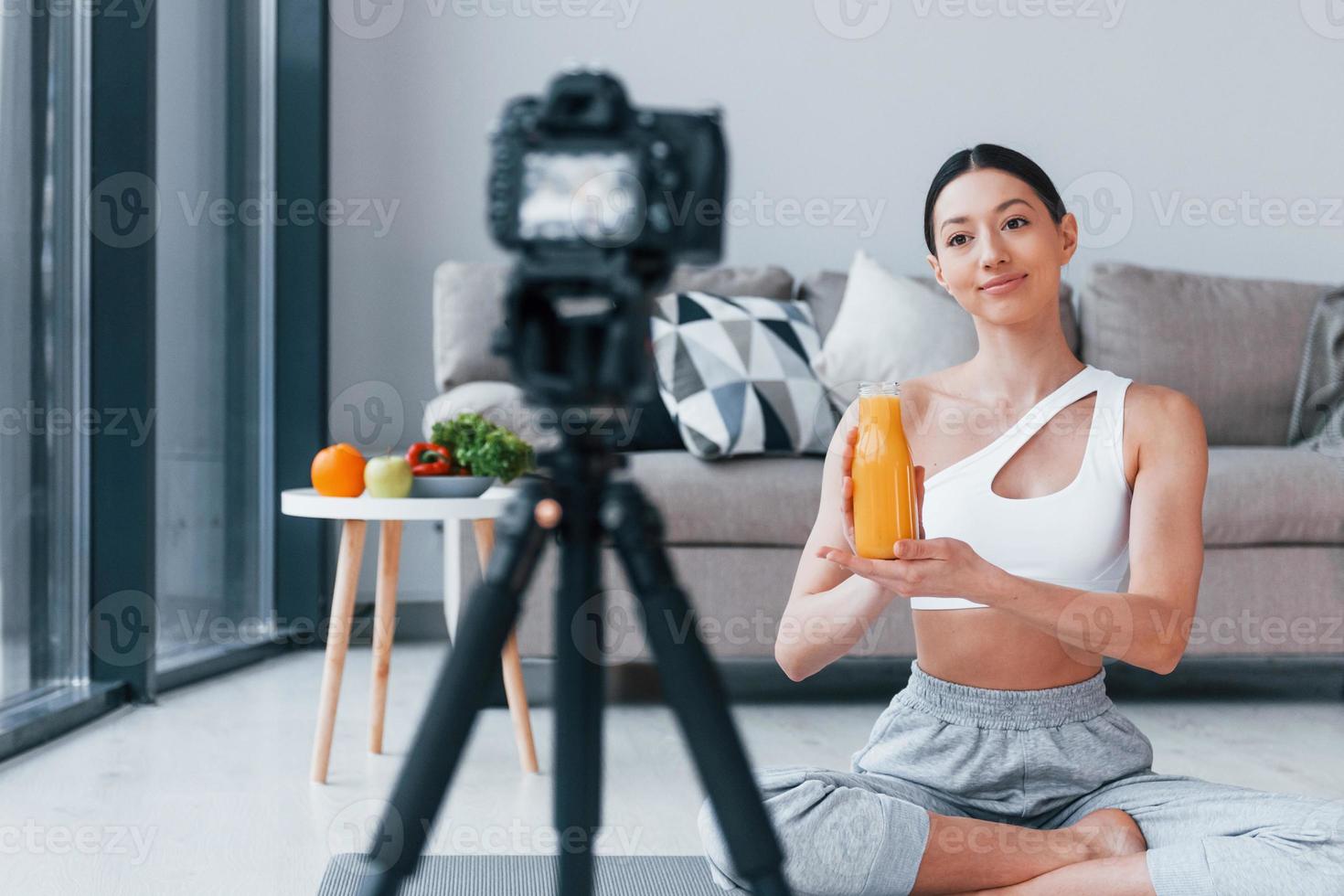 blogger junge frau mit schlanker körperform in sportbekleidung, die zu hause über gemüse, obst und gesunde lebensmittel spricht foto