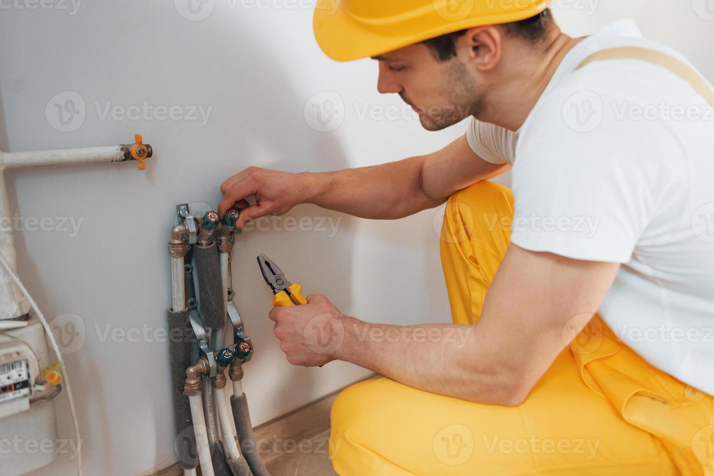 Handwerker in gelber Uniform arbeitet drinnen. haussanierungskonzept. neues Gerät installieren foto