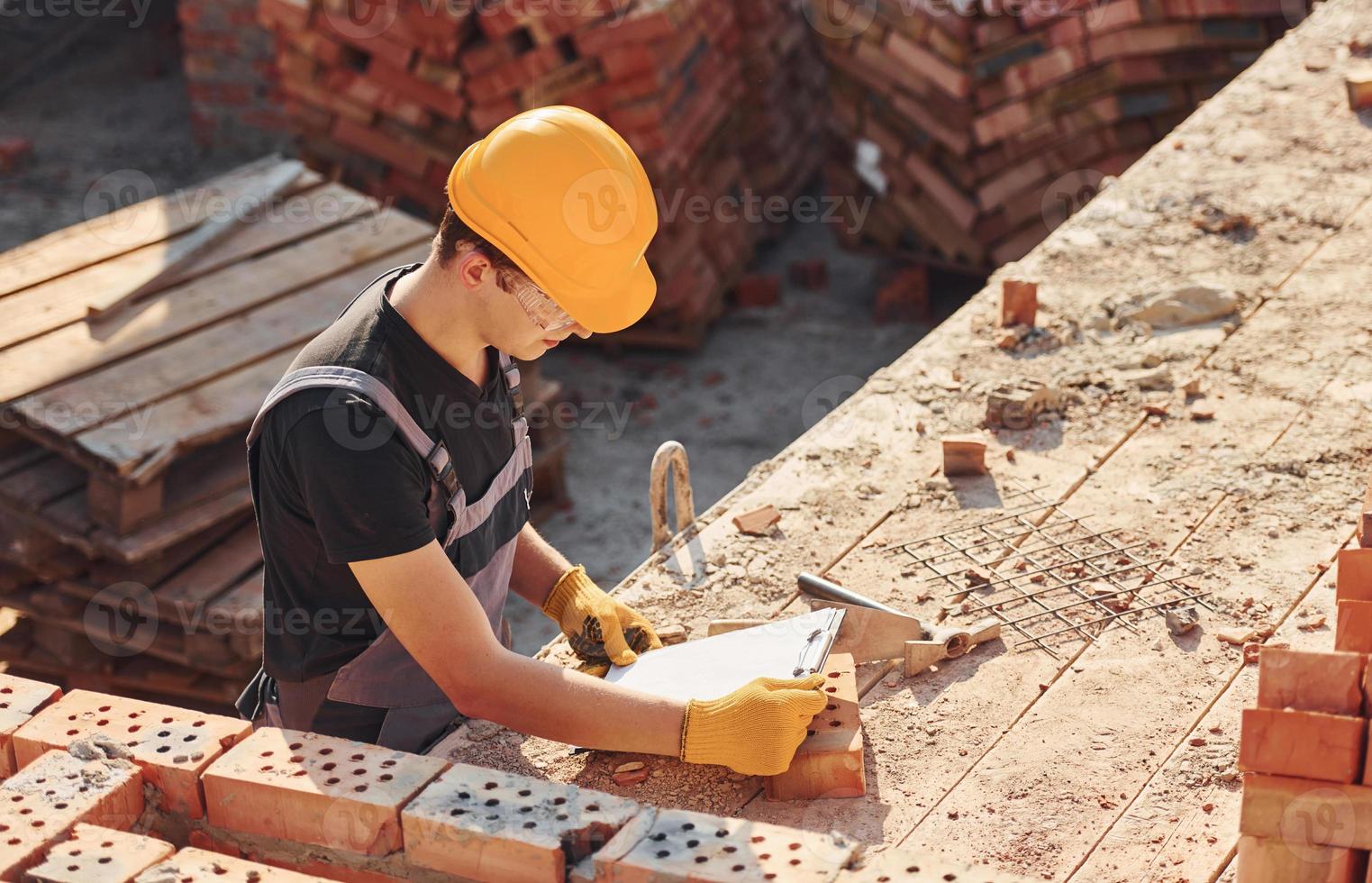 Plan in Händen halten. bauarbeiter in uniform und sicherheitsausrüstung haben arbeit am bau foto