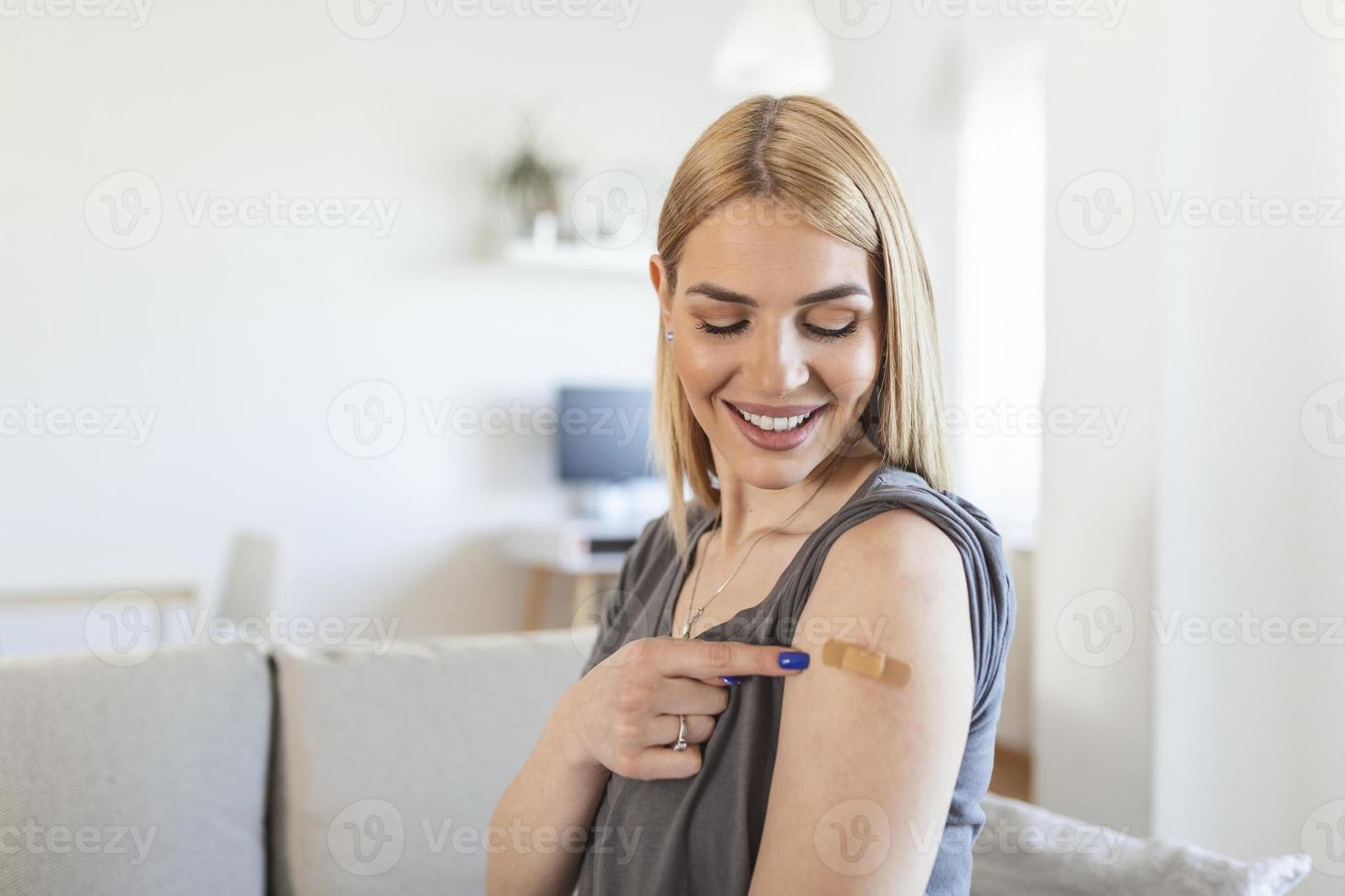 frau, die mit einem verband auf seinen arm zeigt, nachdem sie den covid-19-impfstoff erhalten hat. junge frau, die ihre schulter zeigt, nachdem sie einen coronavirus-impfstoff erhalten hat foto