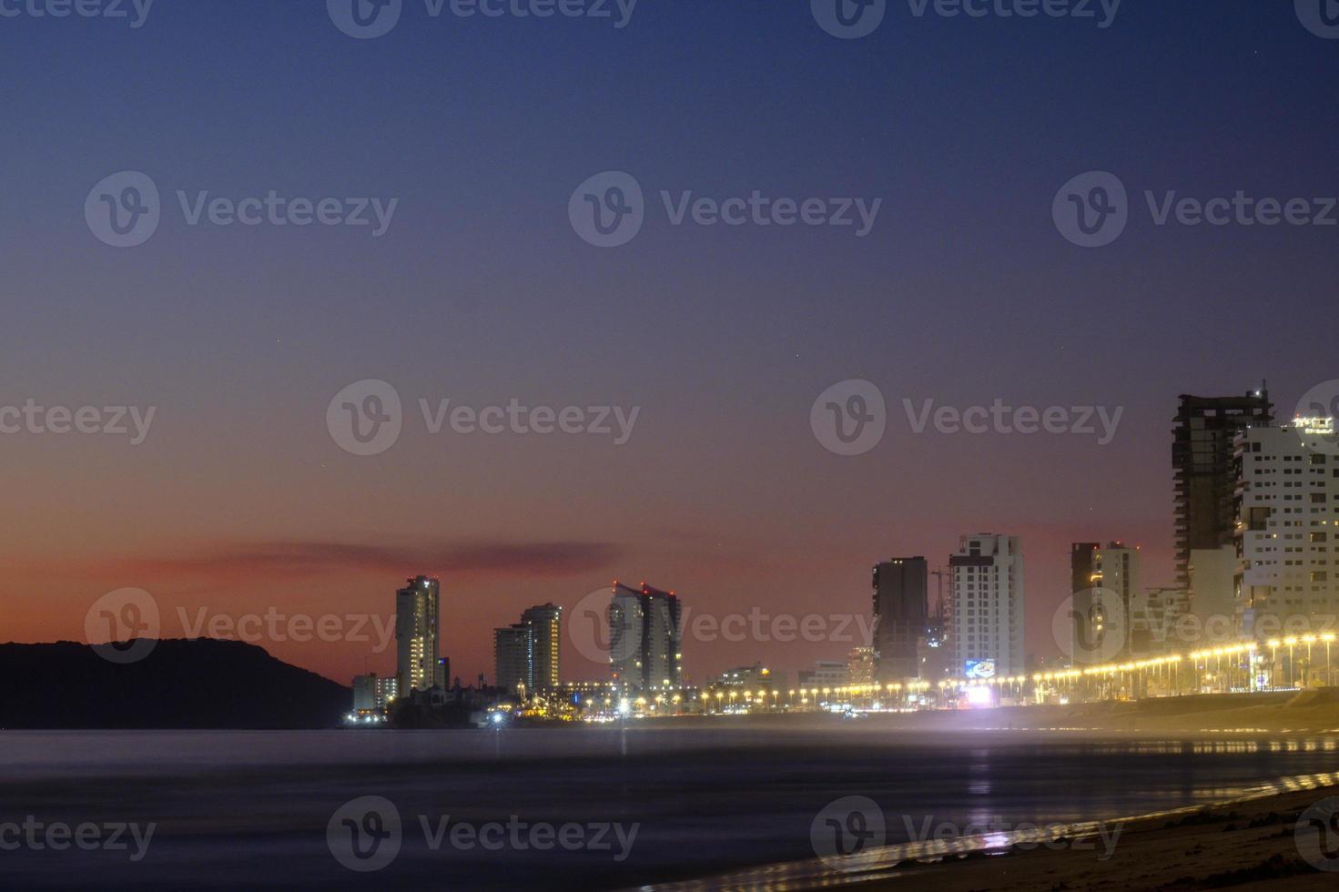 mazatlan sinaloa beach bei nacht mit leuchtender stadt im hintergrund foto