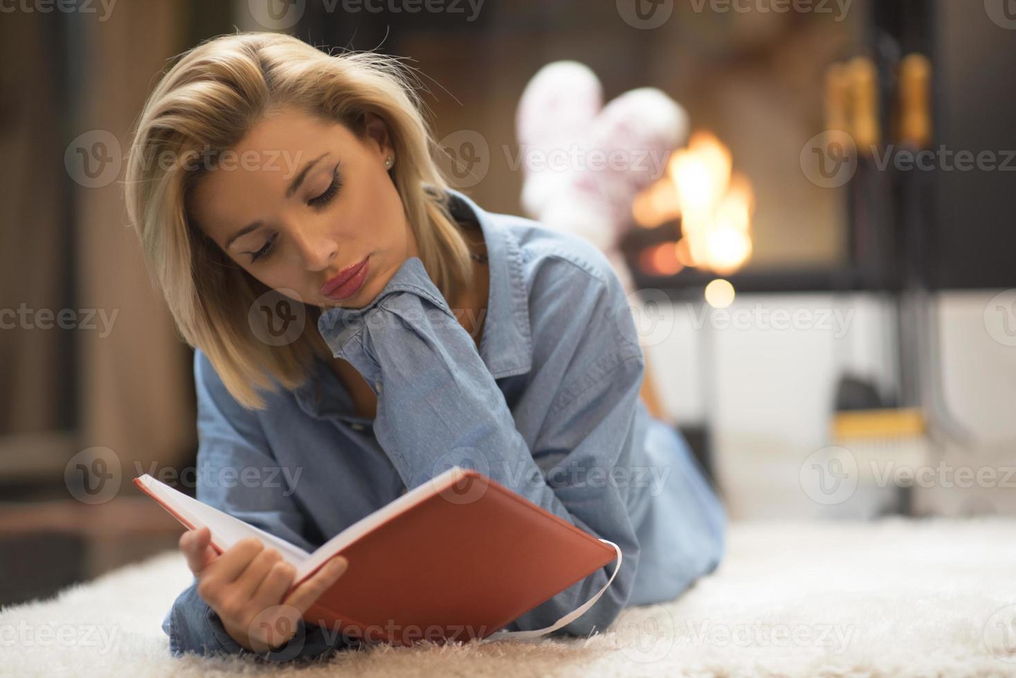 blonde Frauen an einem Kamin, die ein Buch lesen. Life-Stil-Konzept foto