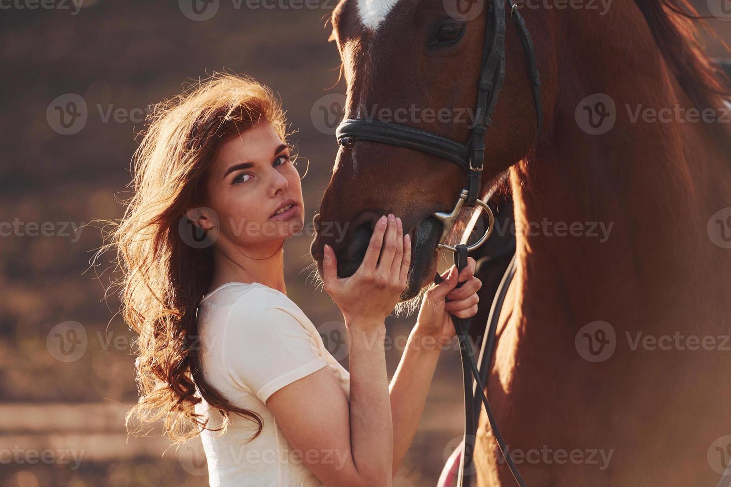 junge frau, die tagsüber mit ihrem pferd auf dem landwirtschaftsgebiet steht foto