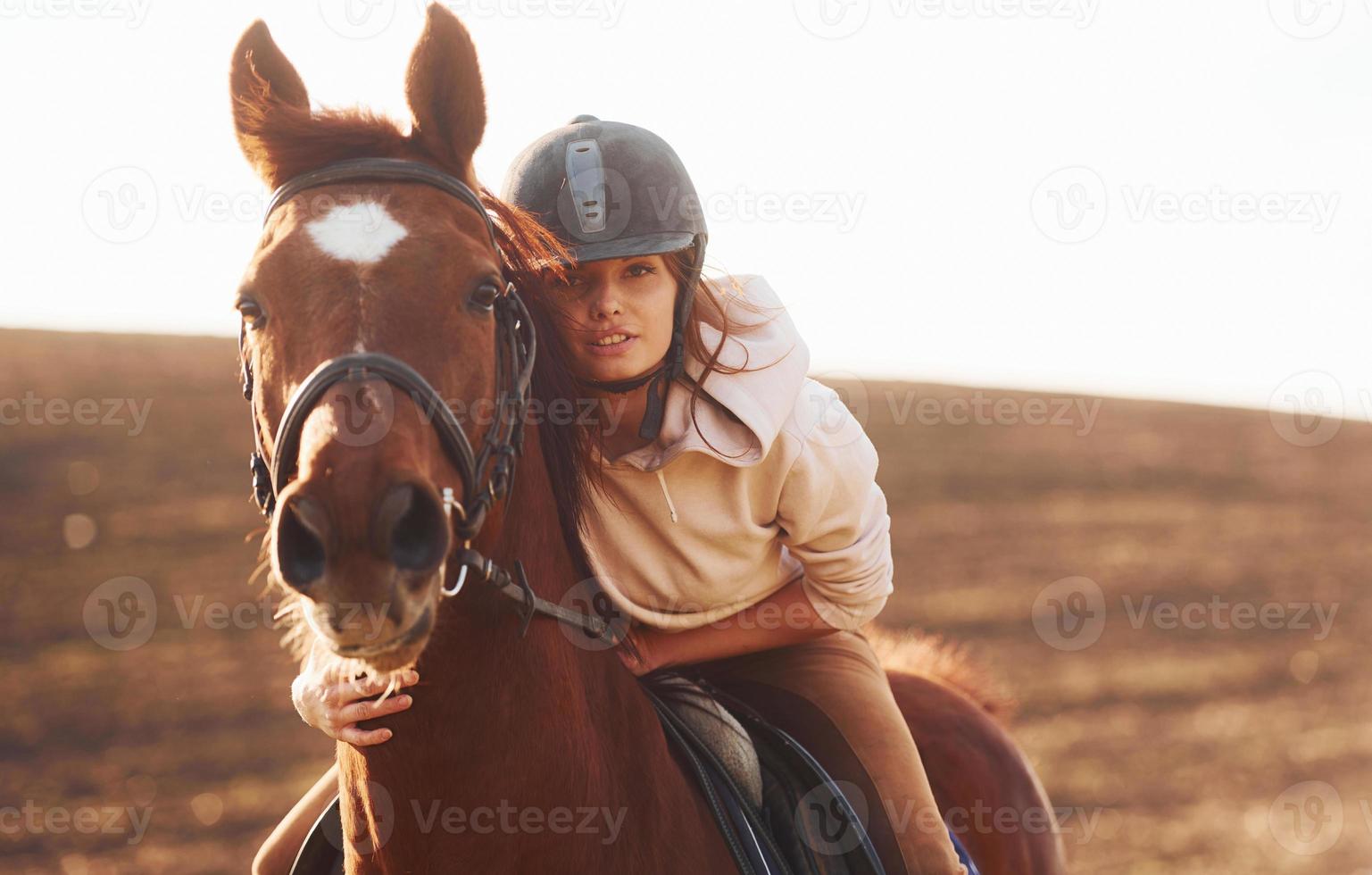 junge frau mit schutzhut mit ihrem pferd auf dem landwirtschaftsgebiet bei sonnigem tag foto