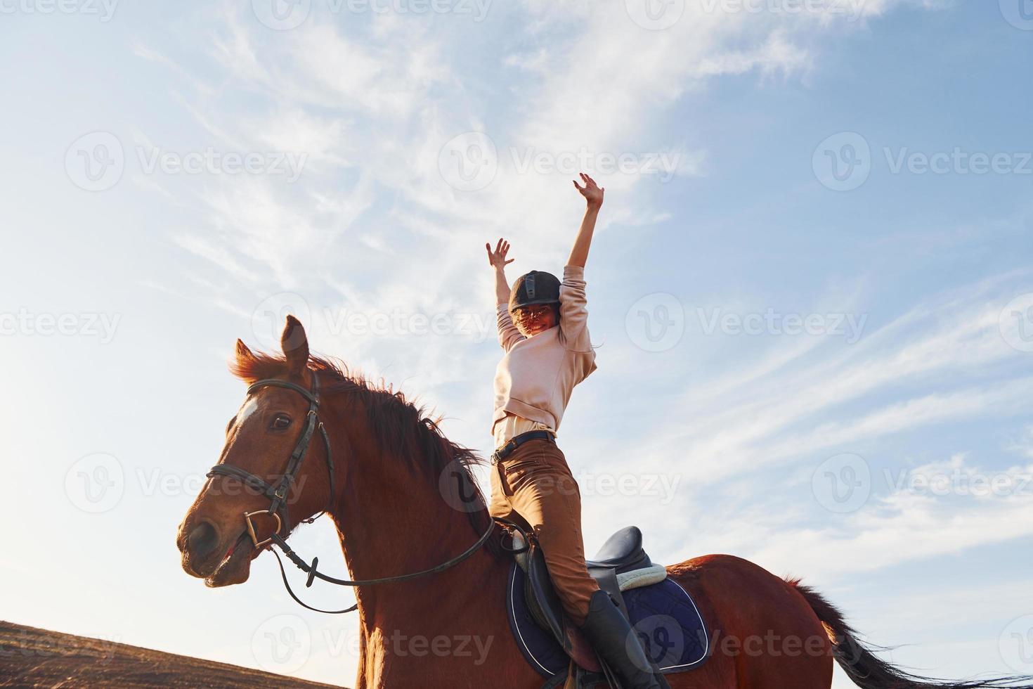 junge frau mit schutzhut mit ihrem pferd auf dem landwirtschaftsgebiet bei sonnigem tag foto