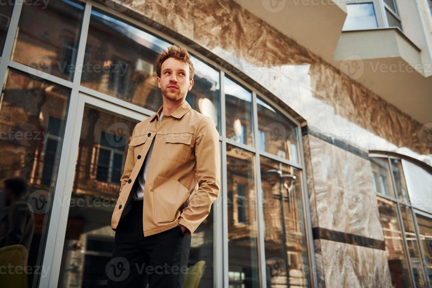 Eleganter junger Mann in formeller, stilvoller Kleidung im Freien in der Stadt in der Nähe des Gebäudes foto