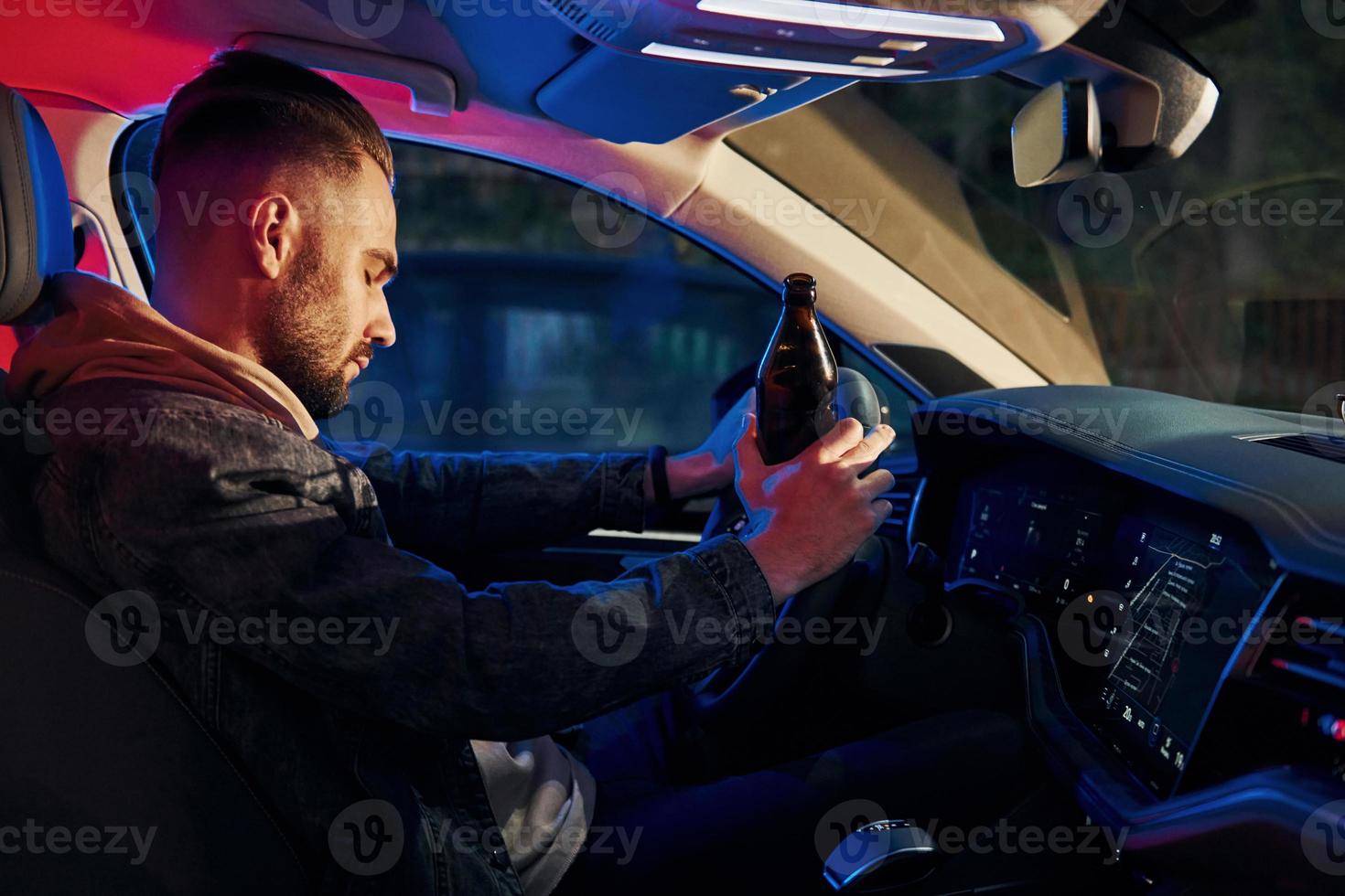 schwarze und rote Polizeilichter. nicht trinken und fahren. Seitenansicht eines gutaussehenden unrasierten Mannes in modischer Kleidung in seinem Auto foto