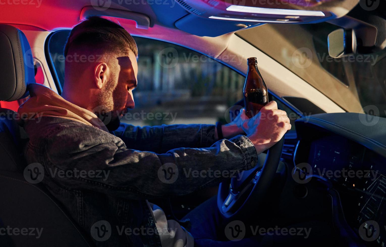 schwarze und rote Polizeilichter. nicht trinken und fahren. Seitenansicht eines gutaussehenden unrasierten Mannes in modischer Kleidung in seinem Auto foto