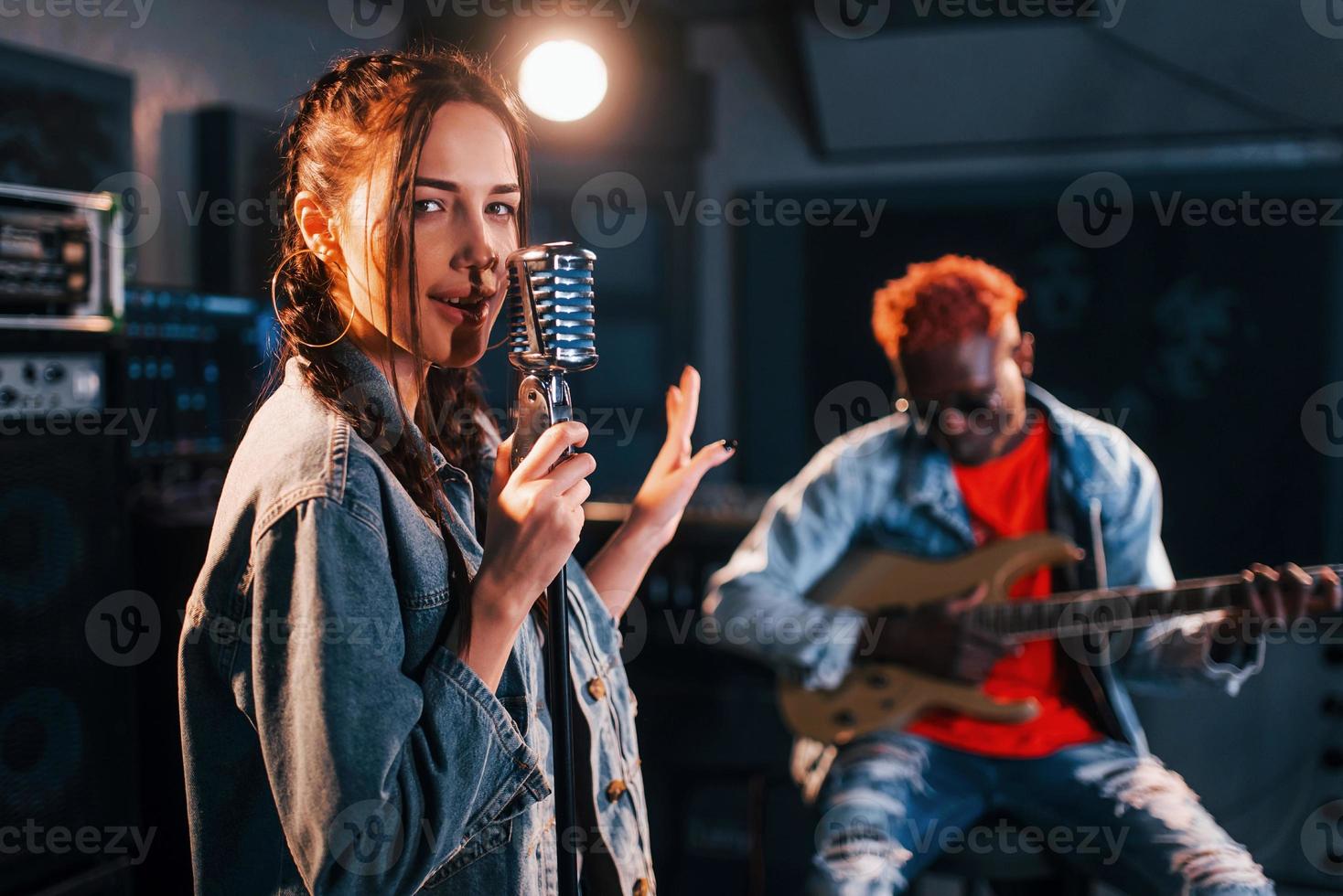 Typ spielt Gitarre, Mädchen singt. afroamerikanischer mann mit weißem mädchen, das zusammen im studio probt foto