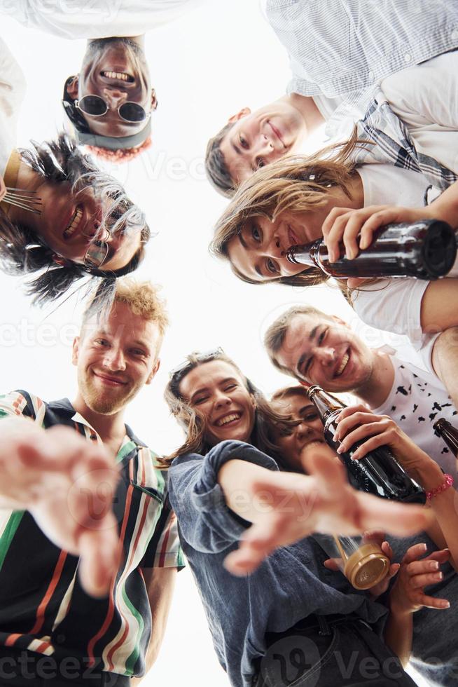 herunterschauen. Ansicht von unten. eine gruppe junger leute in lässiger kleidung feiert tagsüber zusammen eine party auf dem dach foto