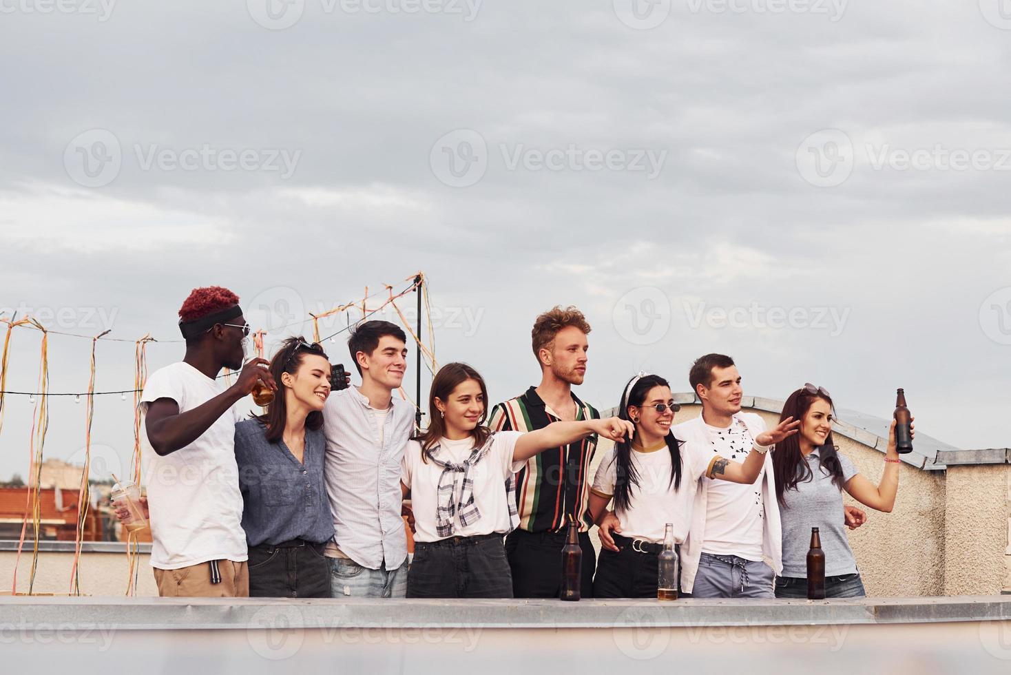 eine gruppe junger leute in lässiger kleidung feiert tagsüber zusammen eine party auf dem dach foto