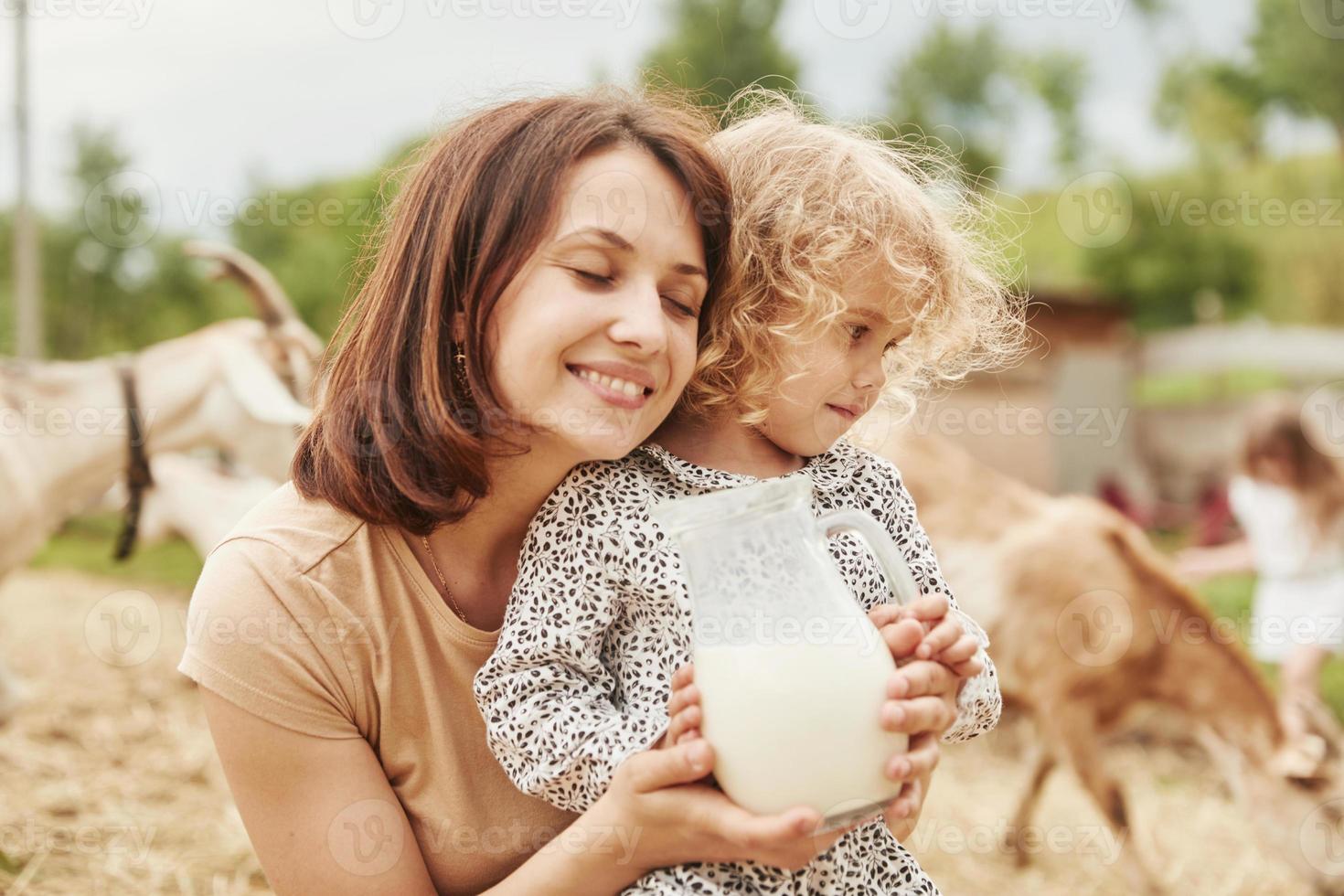 frische natürliche Milch. junge mutter mit ihrer tochter ist im sommer auf dem bauernhof foto