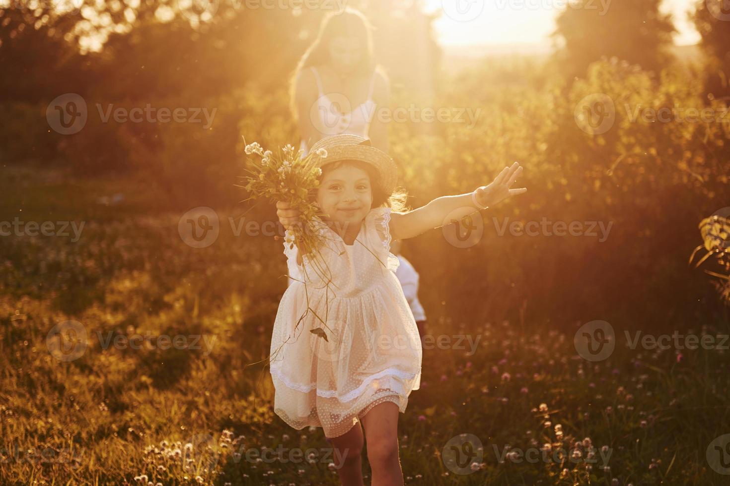 schöner Lichtstrahl. mutter mit jungen und mädchen, die an sonnigen sommertagen freizeit auf dem feld verbringen foto