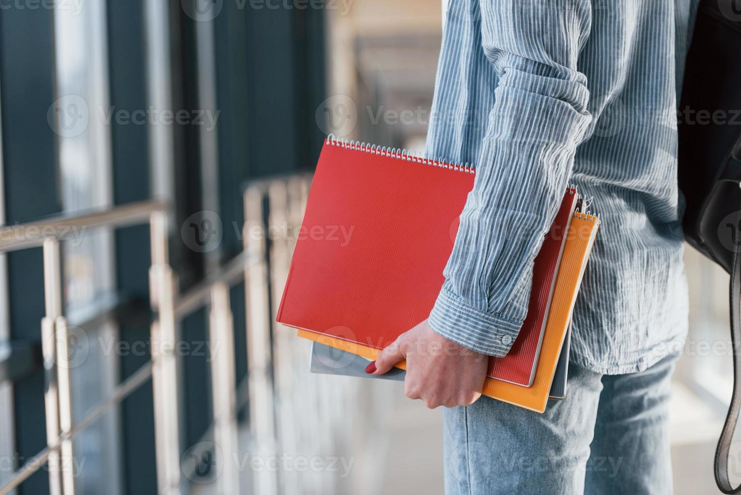 Nahaufnahme einer jungen Studentin, die sich im Korridor eines Colleges befindet und Notizblöcke hält foto