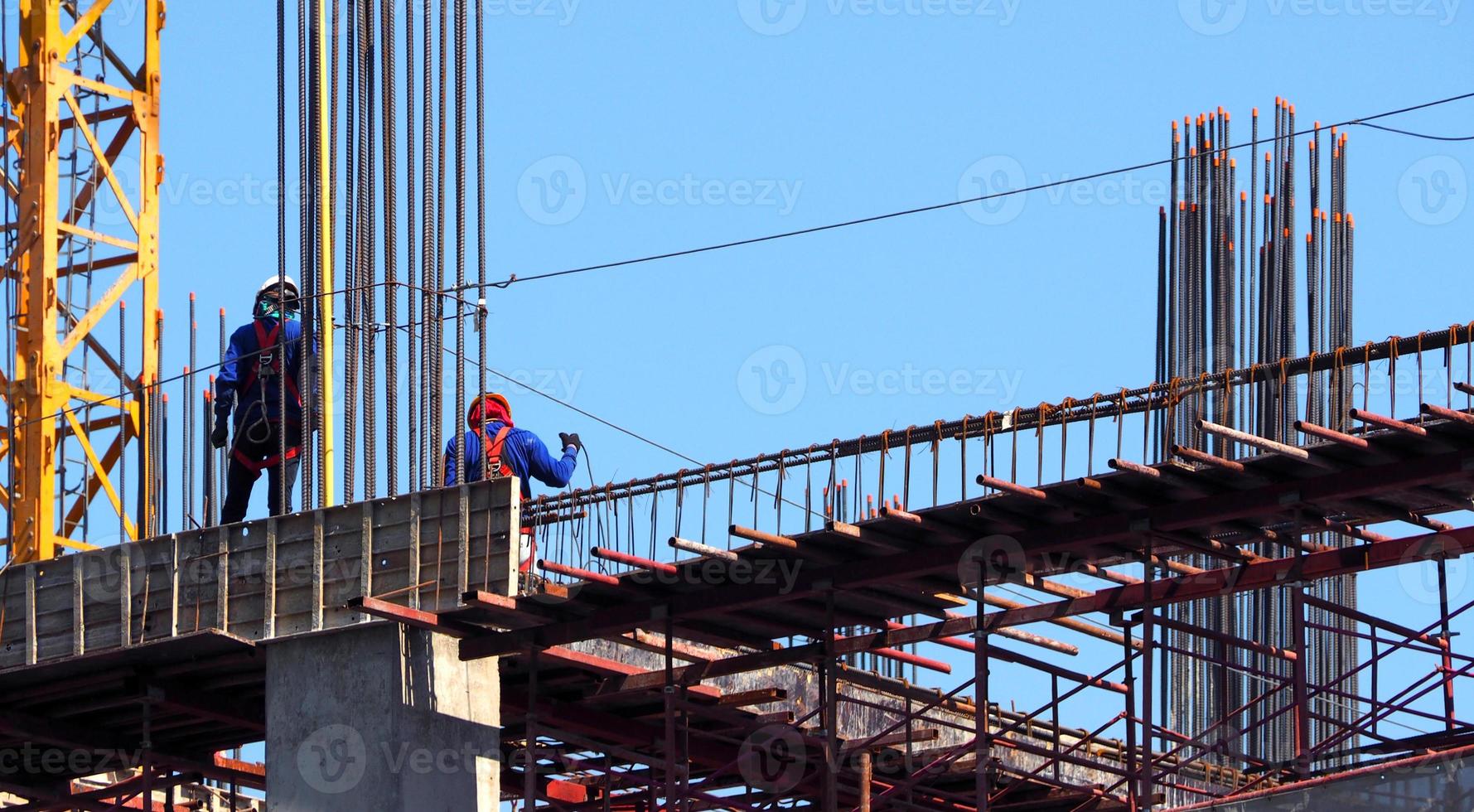 baustelle und arbeiter, die auf stahl- und betonmaterial und blauem himmel stehen. foto