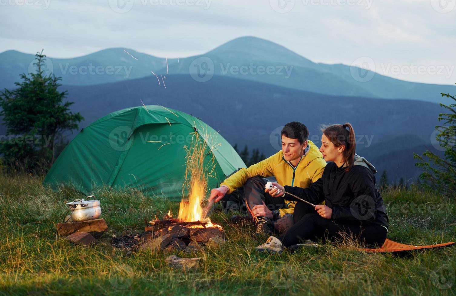 klassische Marshmallow-Zubereitung am Lagerfeuer. junges Paar. majestätische Karpaten. schöne Landschaft unberührter Natur foto