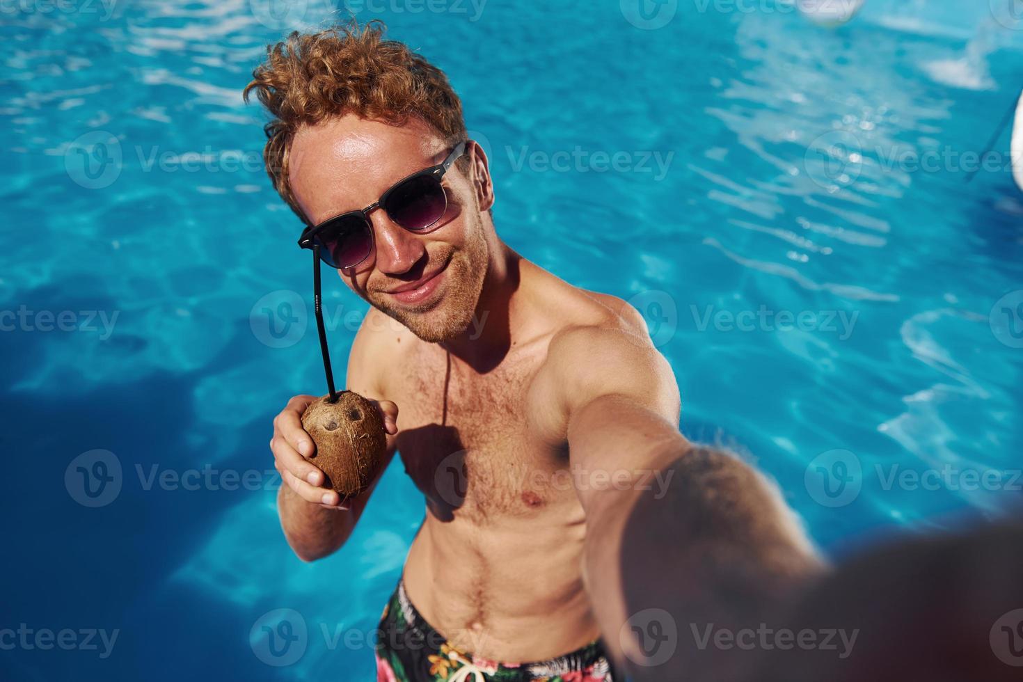 positiver junger mann ruht sich tagsüber draußen im schwimmbad aus foto