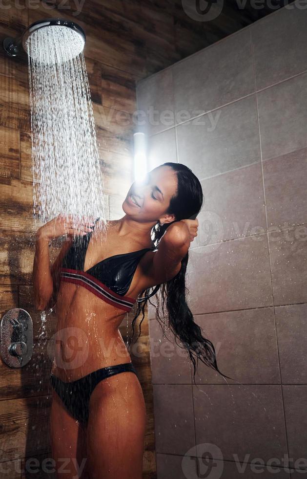 hübsche brünette mit sexy schlankem körpertyp in unterwäsche, die im spa duscht foto