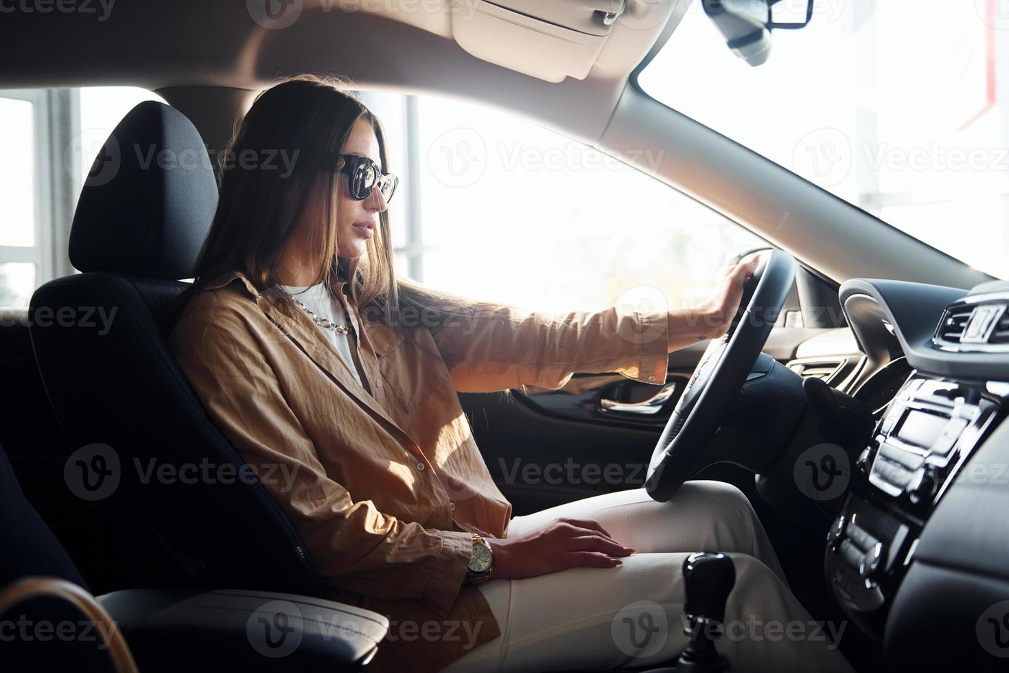 Seitenansicht einer modischen, schönen jungen Frau, die sich in ihrem modernen Automobil befindet foto