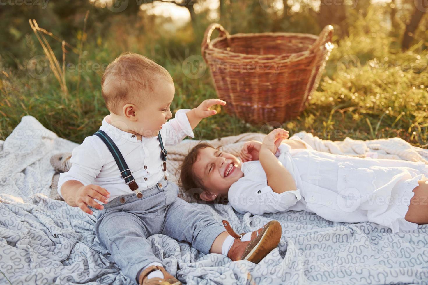 süßer bruder und schwester spielen zusammen im freien mit schönen bäumen und sonnenschein im hintergrund foto