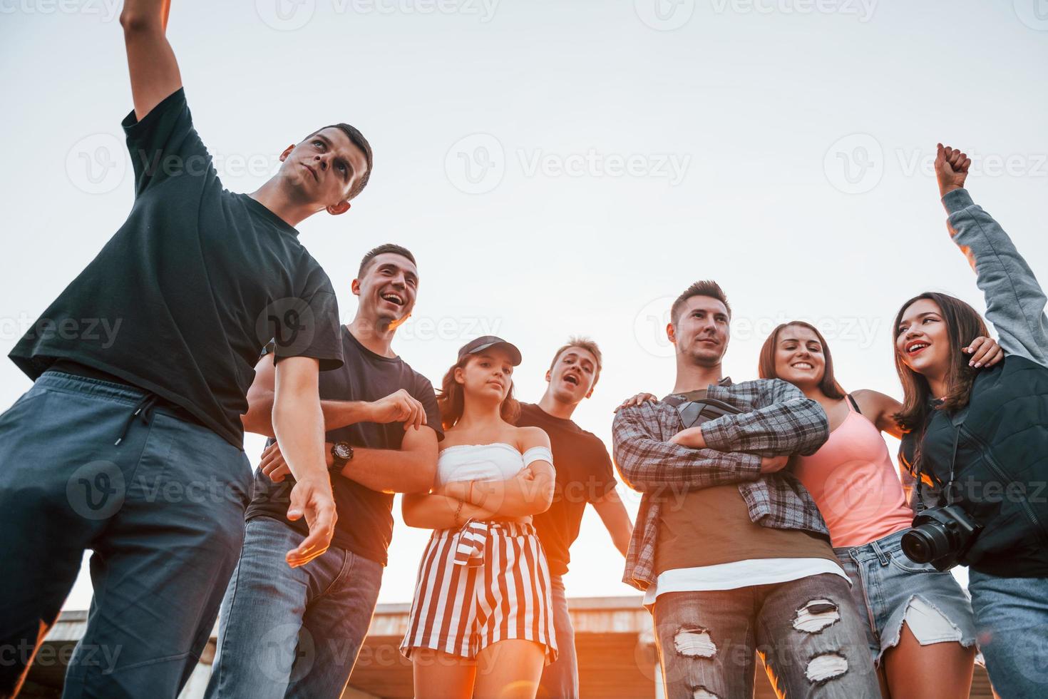 für eine Kamera posieren. gruppe junger fröhlicher freunde, die zusammen spaß haben. draußen feiern foto