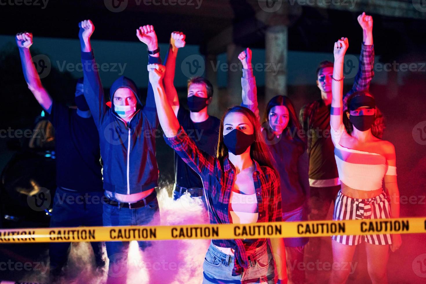 Rauch, Fäuste, Polizei. Gruppe protestierender junger Menschen, die zusammenstehen. Aktivist für Menschenrechte oder gegen die Regierung foto