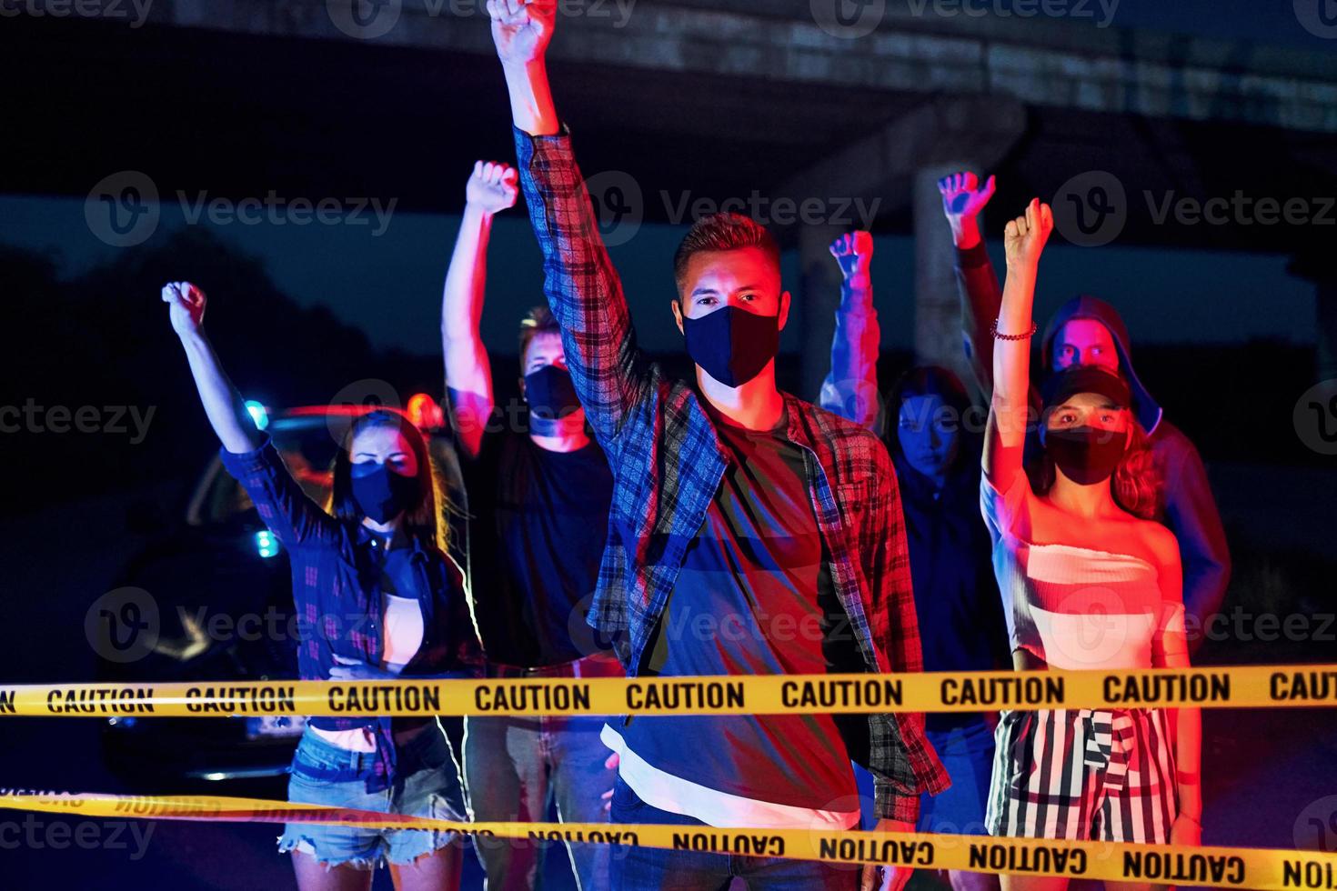 rote und blaue Polizeibeleuchtung. Gruppe protestierender junger Menschen, die zusammenstehen. Aktivist für Menschenrechte oder gegen die Regierung foto