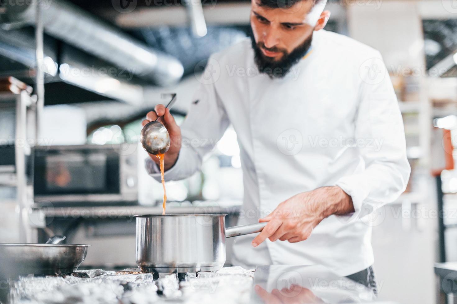 kocht leckere Suppe. Koch in weißer Uniform, der Essen in der Küche kocht. arbeitsreicher Tag foto