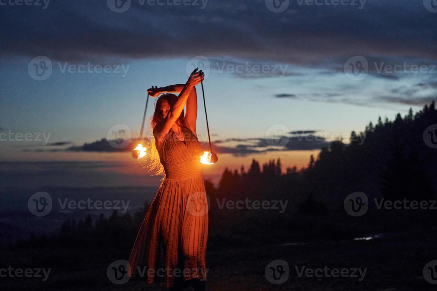 Feuershow von Frau im Kleid in den nächtlichen Karpaten. schöne Landschaft foto