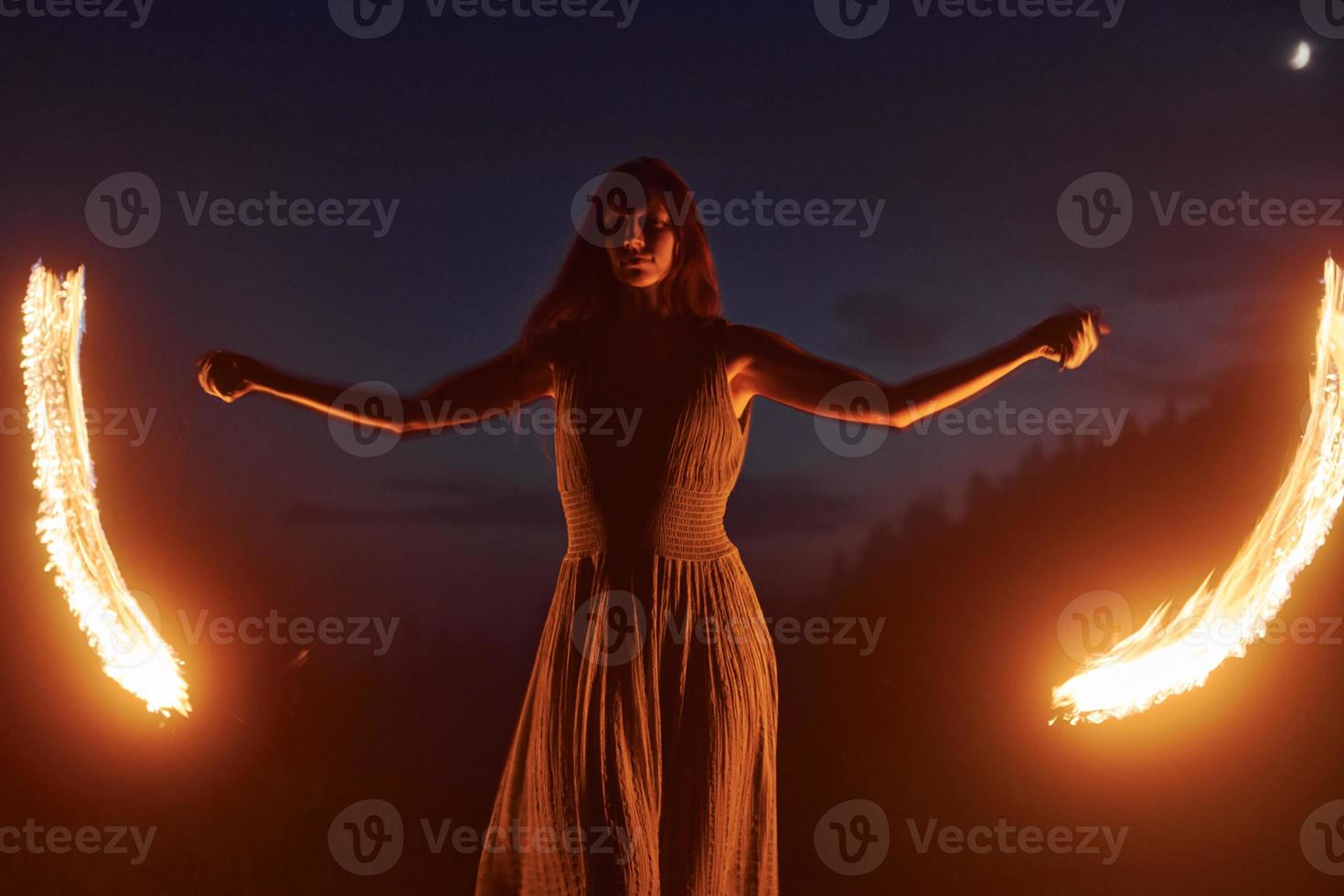 Foto mit Langzeitbelichtung. Feuershow von Frau im Kleid in den nächtlichen Karpaten. schöne Landschaft