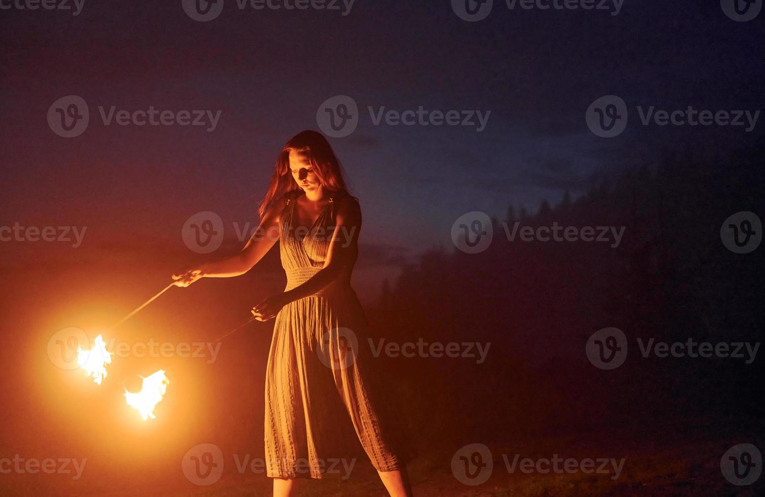 Feuershow von Frau im Kleid in den nächtlichen Karpaten. schöne Landschaft foto