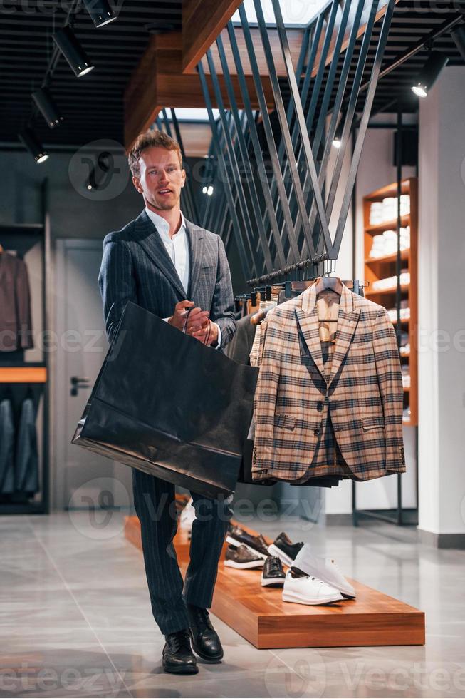 Einkaufstag. junger mann im modernen geschäft mit neuen kleidern. elegante teure kleidung für männer foto