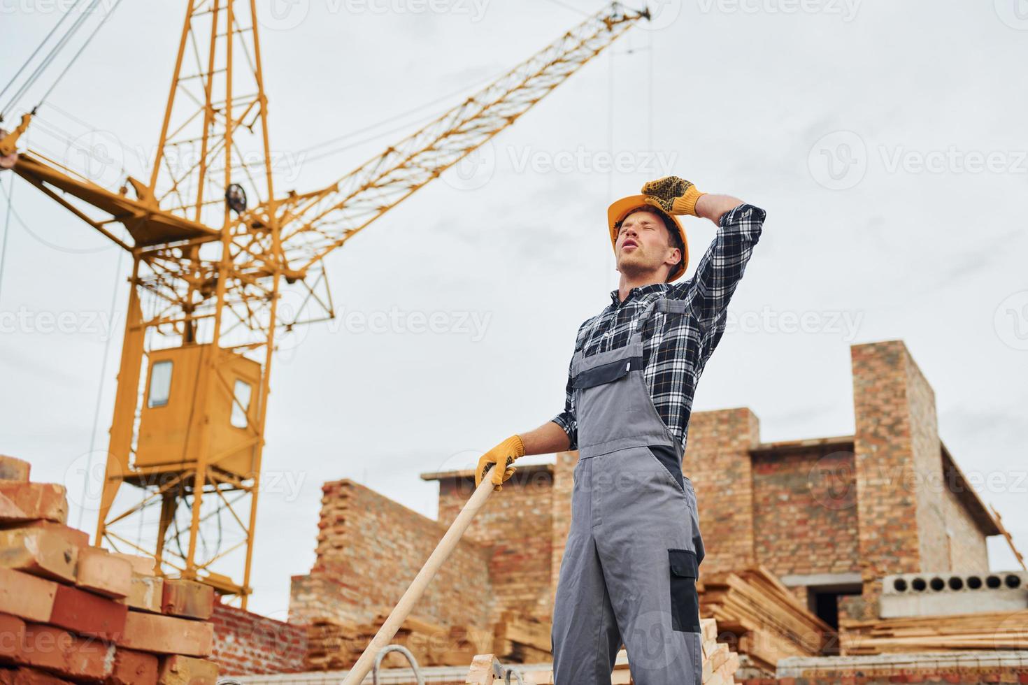 mit Schaufel in der Hand. bauarbeiter in uniform und sicherheitsausrüstung haben arbeit am bau foto