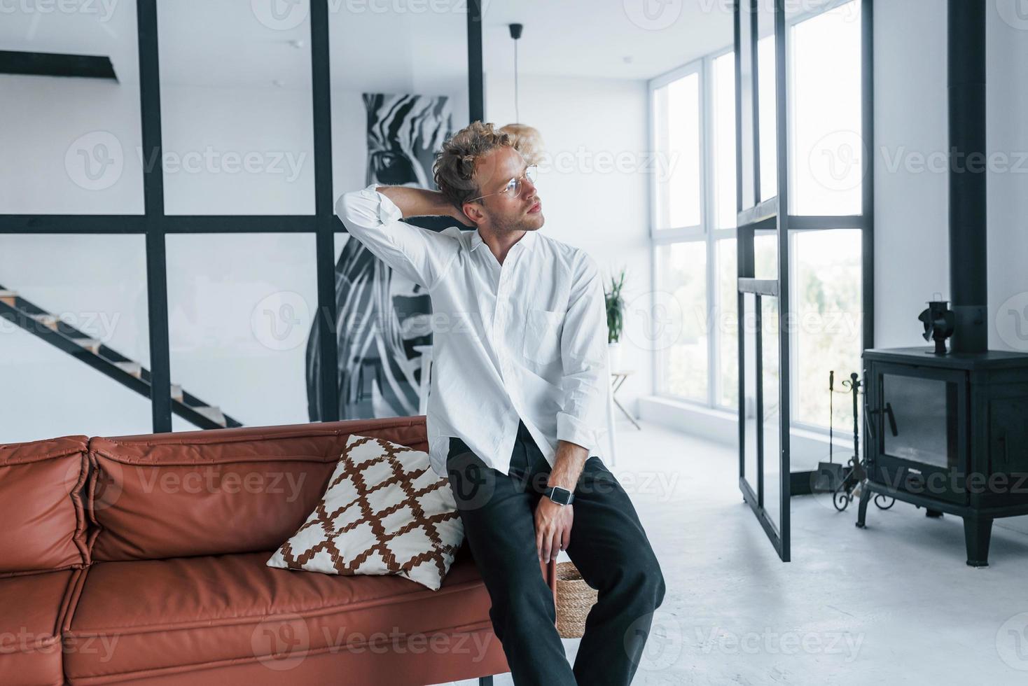 schönes Interieur. kaukasischer junger kerl im eleganten weißen hemd zuhause zu hause foto