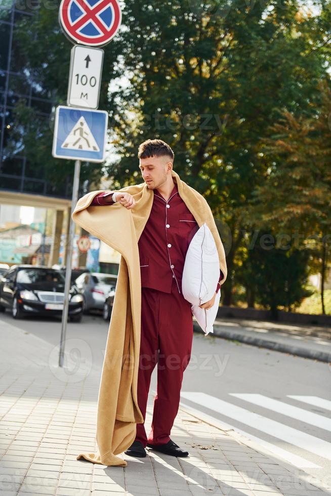 junger mann im pyjama ist draußen auf der straße. fühlt sich schläfrig foto