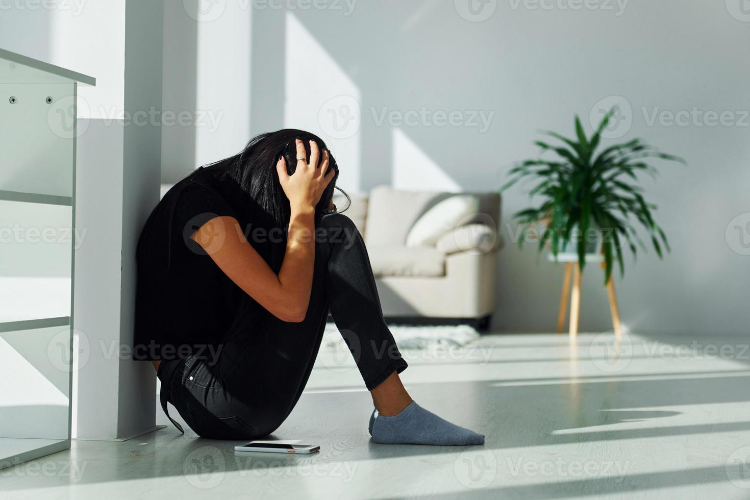 junge frau in lässiger kleidung, die allein zu hause weint. Teddybär auf dem Boden liegend foto