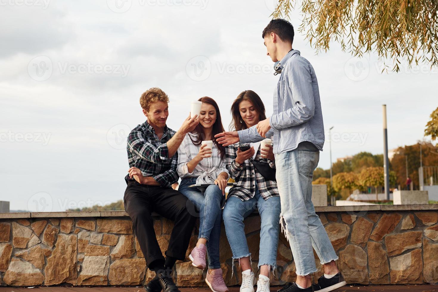 Kaffeezeit. Gruppe junger, fröhlicher Freunde, die draußen Spaß haben foto