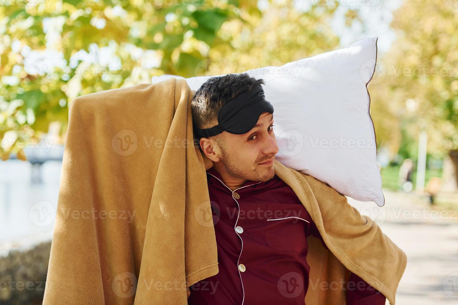 junger mann im pyjama ist draußen auf der straße. fühlt sich schläfrig foto